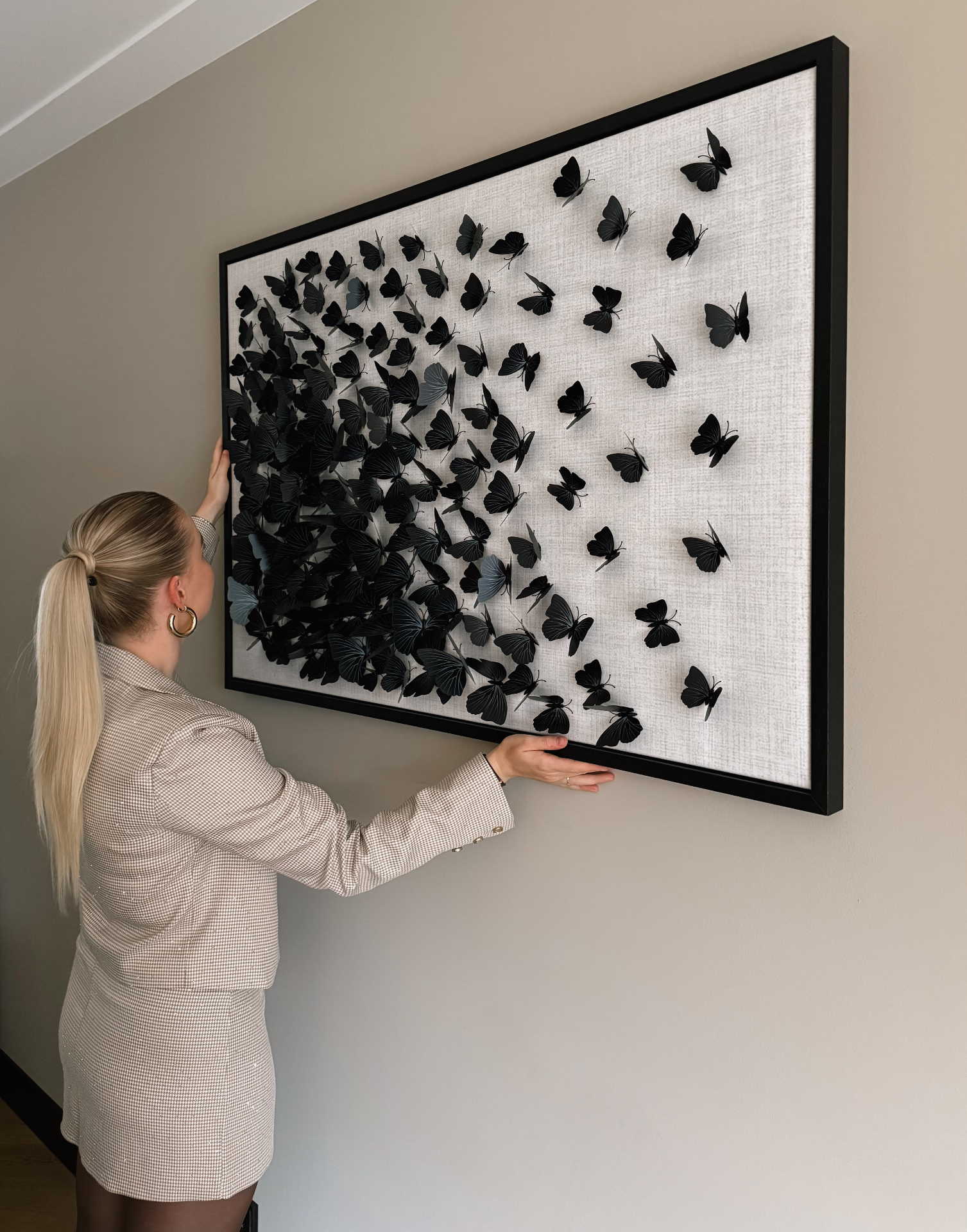Bibi Derks-Steenbergen naast een wanddecoratie met vlinders